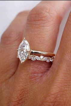 a woman's hand with a diamond ring on top of her finger and the other half of her wedding band