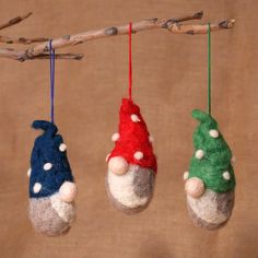 three gnome ornaments hanging from a tree branch