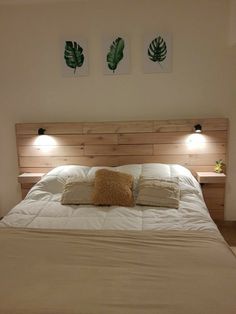 a bed with two lamps on either side of the headboard and night stands above it