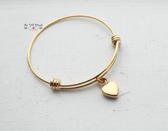 "This cremation urn bangle is made from gold plated stainless steel. Neither the bangle nor the heart shaped urn charm will rust or tarnish. The bangle is expandable, so it will fit most wrists. The gold plated heart shaped urn charm measures approximately 17mm (.7\"). The charm can be stamped with an initial upon request. The bracelet is approximately 60mm (fits 7\" to 9\") wrists. Please note when ordering that you will have to expand the bangle over your hand, so it does need to be larger tha Gold Stainless Steel Heart Bracelet For Anniversary, Nickel-free Gold Heart Bracelet As Gift, Nickel-free Gold Heart Bracelet For Gift, Gold Bangle Charm Bracelet With Heart Charm, Gold Stainless Steel Heart Bracelet As Gift, Gold Nickel-free Heart Bracelet For Gift, Gold Stainless Steel Bracelet With Heart Charm, Minimalist Gold Bangle Heart Bracelet, Gold Heart-shaped Bangle For Anniversary