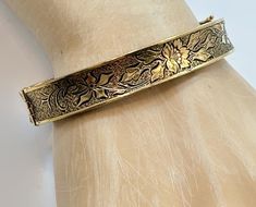 This is a Victorian Revival, hinged bangle from the. 1930's - 40's. I love this bracelet both in style and condition! It is 12K gold filled.  This has a beautiful etched and textured pattern to it. It features a floral pattern.  The background has a texture to make the flower stand out. It features a slide clasp that is in perfect working order with an attached safety latch for extra protection. Beautiful piece on its own or stack it with more for a statement look.  If you want a pair, I have a second one listed!  Condition: Very good vintage condition, vintage patina consistent with age - I do not see any wear! Measurements: 0.43" or 10.71 mm wide; inside measurement 7" around Weight: 17.2 grams Markings: 1/20 12KTGF and what looks like 3 initials that I cannot make out Please examine pho Victorian Bracelet, Victorian Revival, Flower Stand, Flower Stands, Hinged Bangle, Bracelet Gold, Etching, Bangle Bracelets, Gold Filled