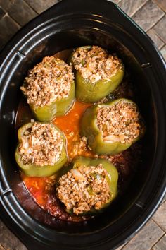 stuffed peppers in a slow cooker with sauce and ground meat on top, ready to be cooked