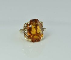 Super 14K Yellow Gold Large Orange Citrine and Diamond Cocktail Ring, octagonal 22 x 15 mm orange yellow center 30 ct est., 8 round diamond accents, millegrained diamond mounts in tendrel like side mounts, Ring size 6.5 and ring guard, Circa 1970, 10.4 grams Stock # BB233R06 Most rings are sizable for a small fee. If the ring you are considering is the incorrect size contact us for a quote. This listing contains photographs of the actual item you will receive.  Our items are in excellent condition with little or no signs of wear and many are one of a kind pre-owned estate finds.   Please look closely at the pictures in this listing as they are part of the product description. Please read the description, as any imperfections or condition comments will be included.  We do our best to accura Orange Citrine, Ring Guard, Diamond Cocktail Ring, Diamond Cocktail Rings, Gold Orange, Fine Jewelry Designers, Yellow Gold Earring, Blue Topaz Ring, Orange Gold