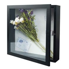 a bunch of flowers that are inside of a glass case on a white surface,