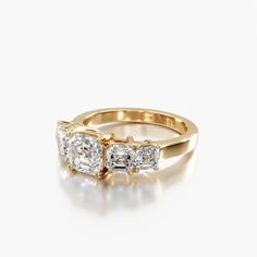 three stone diamond ring in yellow gold with two diamonds on each side and an invisible band