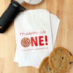 two chocolate chip cookies next to a paper bag with the message mason is one