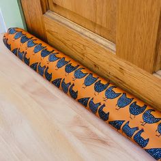 an orange and blue patterned umbrella sitting on the floor next to a wooden door way