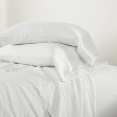 white sheets and pillows are stacked on top of each other