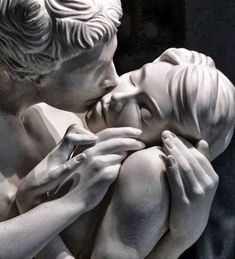 a statue of a man holding a woman in his lap and kissing her cheek with both hands