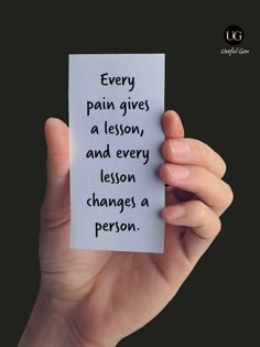 someone holding up a piece of paper that says, every pain gives a lesson and every lesson changes a person