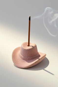 a pink hat with a match stick sticking out of it's center sits on a white surface