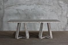 a wooden table sitting in front of a concrete wall with cement flooring and walls behind it