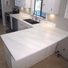 a kitchen with white cabinets and marble counter tops in the middle of the flooring