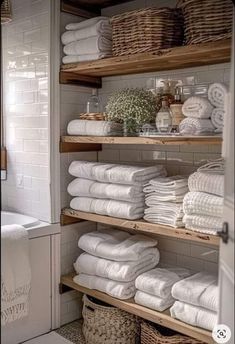 the shelves are filled with white towels and other items in their storage area, along with wicker baskets