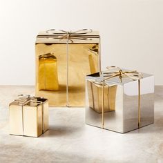 two present boxes wrapped in gold paper and tied with a bow, sitting next to each other