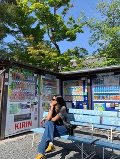 a woman sitting on a blue bench in front of a vending kiosk