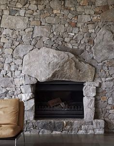 a stone fireplace with a leather chair next to it