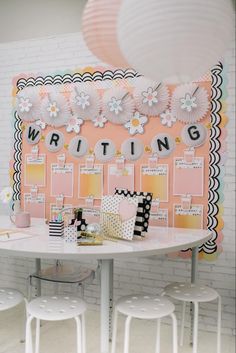 a white table topped with lots of chairs next to a wall covered in writing paper