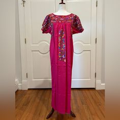 Handmade Embroidered Dress Is From San Antonino Castillo Velasco Region Of Oaxaca, Mex. Each Dress Is One-Of-A-Kind And Characterized By Its Vibrant Colors, Detailed With Silk Embroidery, In Front And The Back And Crochet Work. Pc # E-796 Colors: Fuchsia Or Rosa Mexicano With Multicolor Silk Embroidery Material; Poplin With Multicolor Silk Embroidery Approximate Measurements. Around Bust 46'' Shoulder To Bottom Hem 52” Boho, Bohemian, Handmade, Mexico, Hippie, Embroidery, Vintage, Tunic, One Of Pink Embroidered Dress For Traditional Ceremonies, Traditional Short Sleeve Dress For Fiesta, Traditional Short Sleeve Dress With Embroidered Border, Pink Dress With Embroidered Border For Festive Occasion, Embroidered Short Sleeve Dresses For Traditional Ceremonies, Embroidered Multicolor Maxi Kaftan, Long Embroidered Multicolor Kaftan, Embroidered Maxi Length Pink Kaftan, Traditional Short Sleeve Embroidered Dress For Fiesta