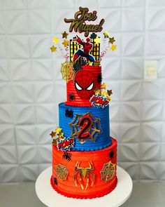 a three tiered cake decorated with spiderman decorations