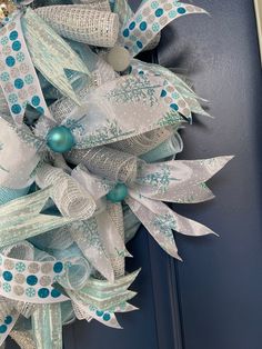 a blue and white christmas wreath hanging on a door