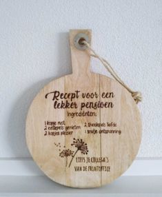 a wooden cutting board hanging on the wall with words written in german and english, as well as a dandelion