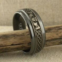 a wedding ring with an intricate design on it sitting on top of a piece of wood