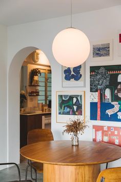 a dining room table with chairs and pictures on the wall