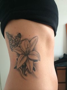 a woman's back with a butterfly and flower tattoo on it