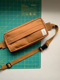 a brown bag sitting on top of a green cutting board next to a knife and ruler