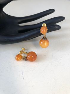 Vintage dangle earrings round amber color plastic balls golden screw clips by Dauplasie. Size 1 1/4" dangle x 1/2" width in good condition. Light weight. Vintage Orange Dangle Earrings, Vintage Orange Pierced Earrings, Vintage Amber Dangle Earrings, Vintage Orange Round Earrings, Vintage Orange Clip-on Earrings, Vintage Orange Earrings, Smokey Topaz, Earrings Round, Art Deco Earrings