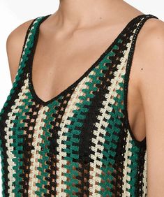 a close up of a woman wearing a green and black top with crochet