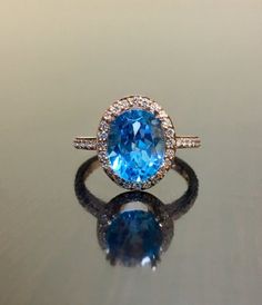 DeKara Designs Collection Our latest design!  An elegant and lustrous Blue Topaz surrounded by beautiful diamonds in a halo setting.Metal- 18K Rose Gold, .750.Stones- Center Features a Oval Fiery Blue Topaz, 11 MM Long, 9 MM Wide, 44 Round Diamonds, G-H Color VS2-SI1 Clarity, 0.35 Carats.Latest of my creations.  A beautiful 18K Rose Gold Blue Topaz Halo Diamond Ring.  The Amethyst is professionally prong set in between 4 double prongs.  There are 10 pave set round diamonds on each side of the sh Luxury Blue Topaz Halo Ring, Luxury Light Blue Ring With Brilliant Cut, Luxury Light Blue Brilliant Cut Ring, Dazzling Blue Diamond Ring, Light Blue Topaz Ring With Diamond Halo Setting, Light Blue Topaz Halo Ring With Diamonds, Formal Rose Gold Topaz Ring With Halo Setting, Luxury Blue Topaz Ring With Brilliant Cut, Dazzling Blue Diamond Ring With Brilliant Cut