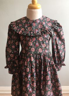 "A beautiful 100% cotton vintage girl's dress from the 1980's with a sophisticated design and print. Jayne Copeland\" is the label and I have found their designs to be very classic and well made. The front bodice is plain with no shaping. It ends in a very narrow self piping at waist above a gathered skirt. Collar is a deep, round \"Bertha\" style with a self frill at outer edge. Sleeves are long with gathers at cap and end in a 1.75\" cuff with a frill at upper edge. (It is difficult to see thi Bertha Collar, Vintage Girls Dresses, Darling Dress, Gathered Skirt, African Attire, Sophisticated Design, Vintage Girls, Cotton Dress, Cotton Dresses