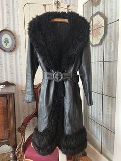 This coat is amazing! It's made from soft black leather and trimmed with decadent black fox fur, on the large collar and one front edge, with a double row of fur along the bottom. It fastens at the waist with two buttons and has a matching belt. The measurements, taken with the coat lying flat, are: shoulder to shoulder, 16 inches; armpit to armpit, 18 inches; sleeves, 24 inches; waist, 18 inches; length, 42 inches; bottom edge, 33 inches. Please note some wear at the neck lining and cuffs - see photos. Overall, the coat is in very good vintage condition. Fitted Black Outerwear With Feather Trim, Black Fur Coat With Feather Trim Long Sleeve, Black Leather Fur Coat With Faux Fur Trim, Black Long Sleeve Fur Coat With Feather Trim, Fitted Black Faux Fur Coat, Black Formal Outerwear With Feather Trim, Formal Black Outerwear With Feather Trim, Black Sheepskin Fur Coat With Faux Fur Lining, Black Sheepskin Leather Jacket With Faux Fur Trim