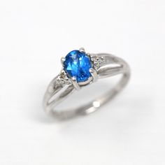 Stunning vintage 10k white gold created spinel and diamond accented ring! This unique modernist style piece features a created blue spinel center weighing 0.48 carats, and two sparkling diamond accents on either side weighing 0.01 carats each. The gemstones are all securely set in prong settings with a lovely, modern cathedral style tapered ring band. A beautiful piece of modern estate jewelry! *Sale - price reduced from $295 USD to $285 USD. ERA - Modern Estate METAL / MATERIAL - 10k white gold Oval Blue Topaz Ring With Diamond Cut, Blue Oval Solitaire Diamond Ring, Oval Blue Sapphire Ring With Diamond Accents, Blue Oval Birthstone Ring With Diamond Accents, Oval White Gold Birthstone Ring With Diamond Accents, Oval Blue Birthstone Ring With Center Stone, Blue Oval Birthstone Ring In Fine Jewelry Style, Oval Sapphire Promise Ring In 14k White Gold, Oval Sapphire Birthstone Ring In White Gold