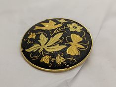 Beautiful Asian Damascene brooch. This brooch has the typical damascene black steel background with intricate genuine gold inlayed carvings. This style if jewelry art originated in Spain and Japan in the 20th century. It is in very good vintage condition, perfect for the damascene jewelry lover. It measures 1.5 inches wide and has a sturdy trombone closure. I'll ensure your order is fulfilled as requested. Visit my shop at: newagainclassics.ca *Dec 7, 2021: Due to record breaking online sales wo Gold Art Nouveau Brooches For Gift, Art Nouveau Gold Brooches As Gift, Collectible Gold Filigree Brooches, Gold Filigree Brooches Collectible, Gold Filigree Brooches For Collectors, Vintage Black Enamel Pin For Gift, Traditional Collectible Round Brooches, Traditional Round Collectible Brooches, Gold Engraved Collectible Brooches