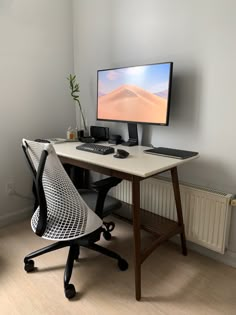 a computer monitor sitting on top of a desk next to a keyboard, mouse and chair