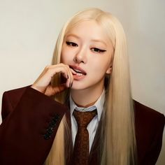 a woman with long blonde hair wearing a suit and tie, posing for the camera