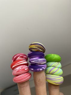 a person's hand with five different colored rings on their fingers, all stacked together