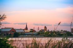 a view of a city from across the water at sunset with buildings in the background