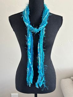 "This handmade scarf consists of a variety of yarns in turquoise. Each of my scarves and no two are ever the same.  Each scarf is made up of a selection of Sari Silk, Eyelash, Ribbon, Ladder, Fuzzy, Sparkly, Pouf Pom Pom, Boucle, Flag Ribbon, Nub, Pluscious, Hand Spun, and Brushbound.  It is approximately 72\" long. This is an open fringe style, secured in three places along the scarf, allowing for styling flexibility, and can be worn as an accent belt.  It is a light weight scarf. Check out this YouTube link https://www.youtube.com/watch?v=5LYAEz777AU for a demonstration of the many ways that you can style this scarf." One Size Blue Shawl For Beach, Bohemian Blue Scarves For The Beach, Blue Bohemian Scarves For Beach, Bohemian Blue Scarves For Beach, Blue Beach Shawl Scarf, Blue Bohemian Silk Scarf For Beach, Bohemian Blue Silk Scarf For Beach, Handmade Bohemian Infinity Scarf One Size, Handmade Blue Shawl For The Beach