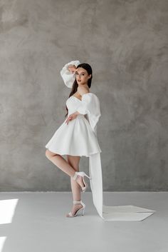 a woman in a white dress posing for the camera with her legs crossed and one leg bent