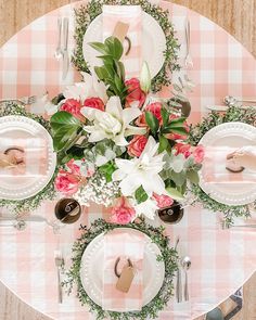 the table is set with pink and white plates, silverware, napkins, and flowers