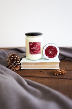 a candle sitting on top of a wooden table next to a book and pine cones