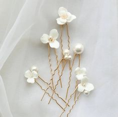 white flowers and pearls are arranged in gold wire