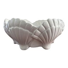 a white shell shaped bowl sitting on top of a table