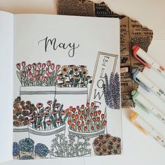 an open book with flowers on it next to some markers and crayon pens