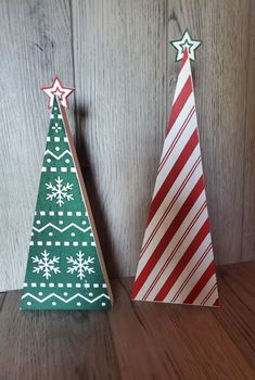 two small wooden christmas trees sitting on top of a wooden table next to each other