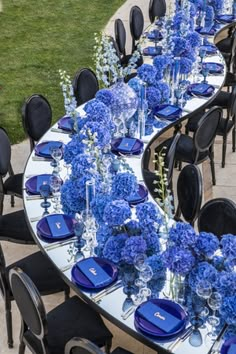 the table is set with blue flowers and place settings for an elegant dinner or party